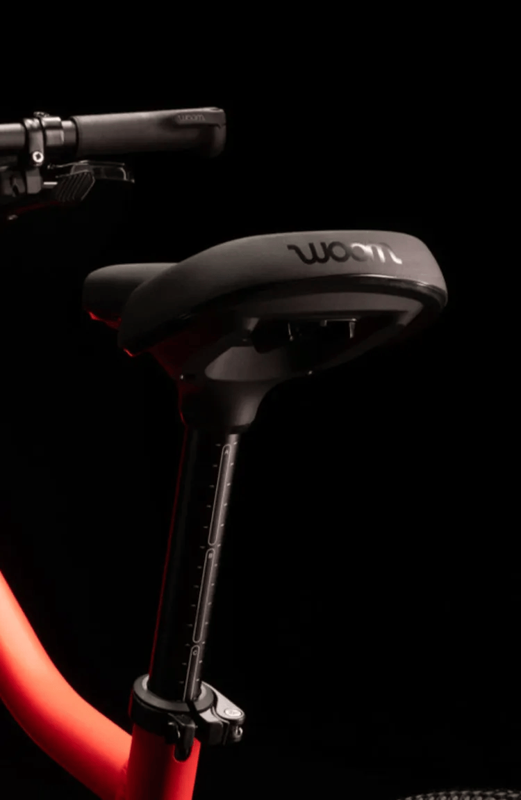 Nahaufnahme eines schwarzen Sattels mit eingraviertem woom Logo auf der Rückseite, montiert auf einem woom EXPLORE Kinderfahrrad.