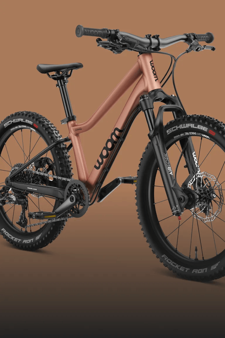 Side front view of the woom OFF AIR kids' mountain bike with front suspension in the color terra coppa