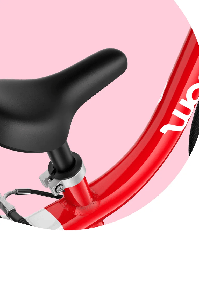 Close-up of the ergonomically profiled bicycle saddle with smooth top surface on a pink woom GO bike